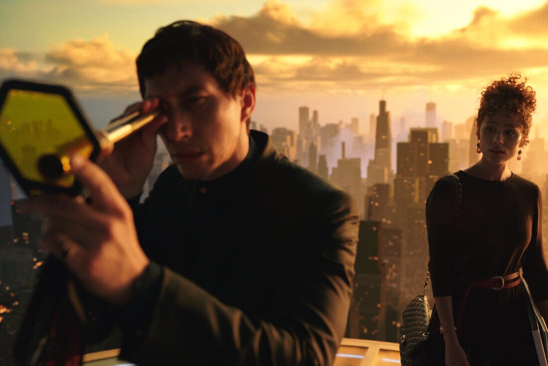 A screenshot from Megalopolis. Adam Driver looks through a telescope while Aubrey Plaza watches