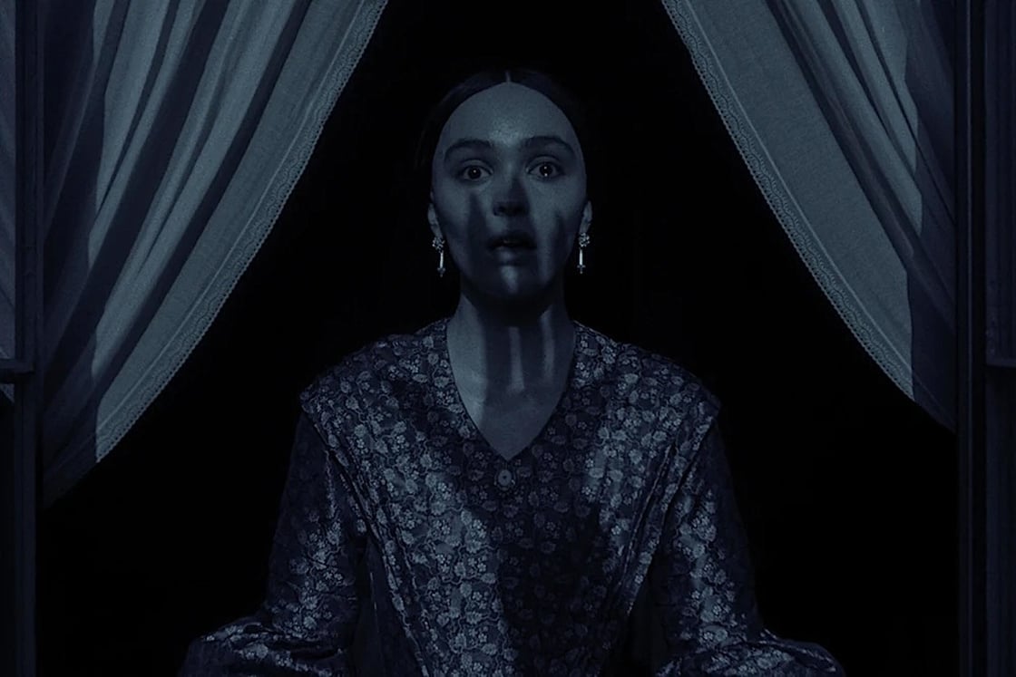 A screencap from Robert Eggers' Nosferatu, showing Lily-Rose Depp's shocked expression as a hand-shaped shadow covers her neck and face.