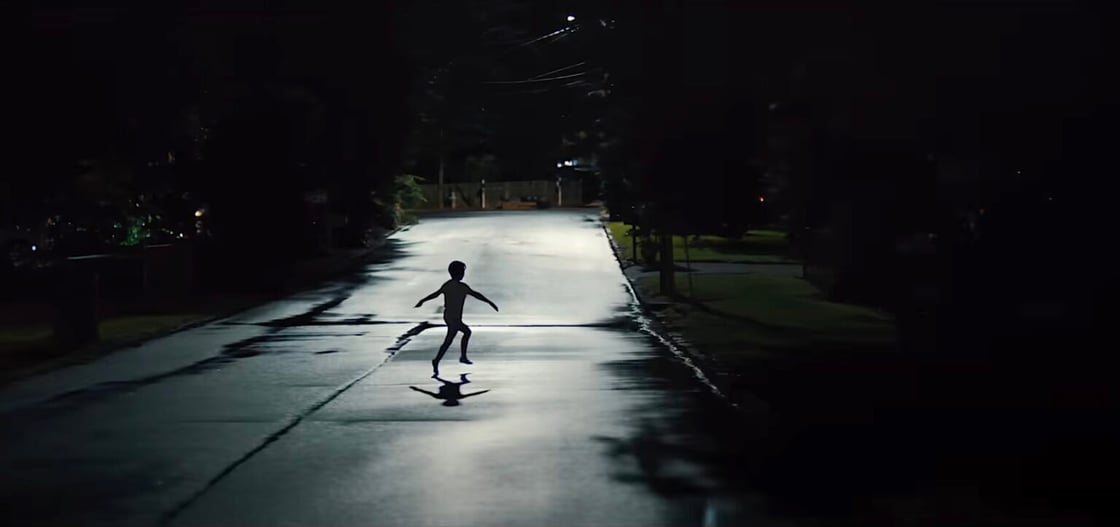 A screencap from Weapons of a child running, arms out, on a suburban street