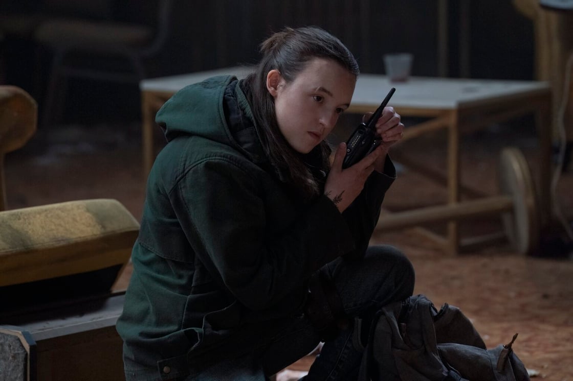 Bella Ramsey in The Last of Us, crouched and holding a small gun