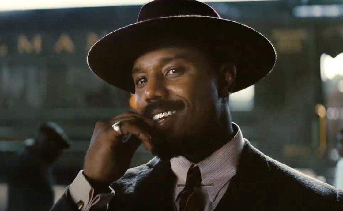 Michael B. Jordan as Stack in Sinners, smiling with a toothpick in his mouth