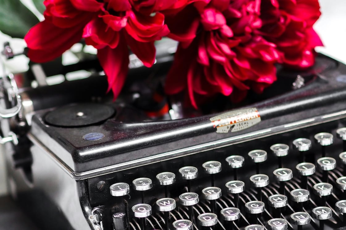A typewriter with red flowers on it