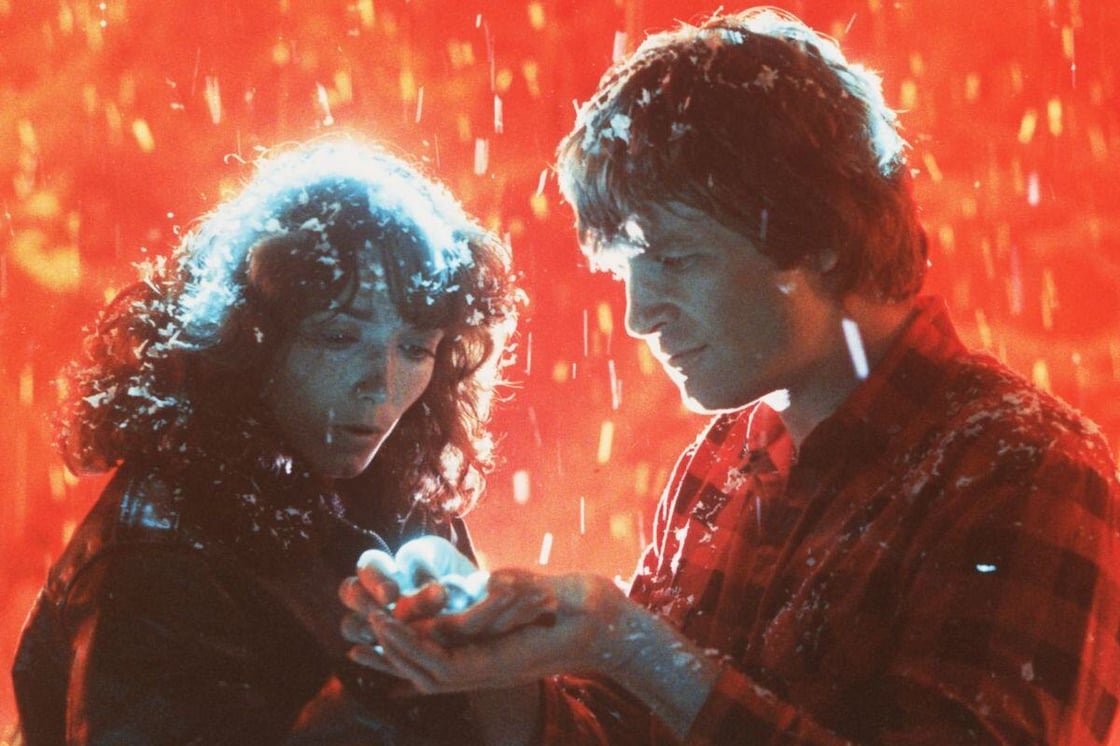 A screencap from John Carpenter's Starman. Jeff Bridges and Karen Allen stare at a blue glowing object in Bridges' hand