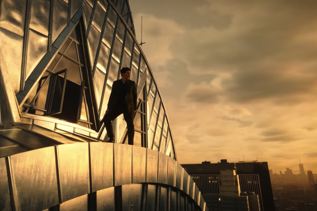 Adam Driver stands on a skyscraper on a cloudy morning; this is a screencap from Megalopolis